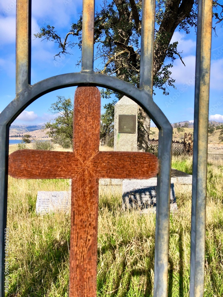 a rusted cross guards the entrance to a historic cemetery dating back to the 1800's near millerton lake state park outside of friant, fresno county, central california