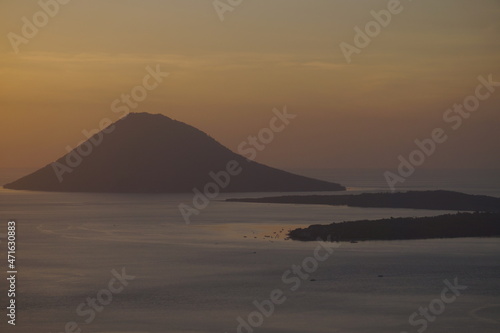 Manado Tua island while sunset with golden skies always looks exotic, North Sulawesi, Indonesia.