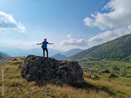 A man enjoying the first sunbeam in the Greater Caucasus Mountain Range in Georgia, Kazbegi Region. The hiker stands on a massive rock near the village of Roshka. Georgian Dolomites. Freedom. Sunrise