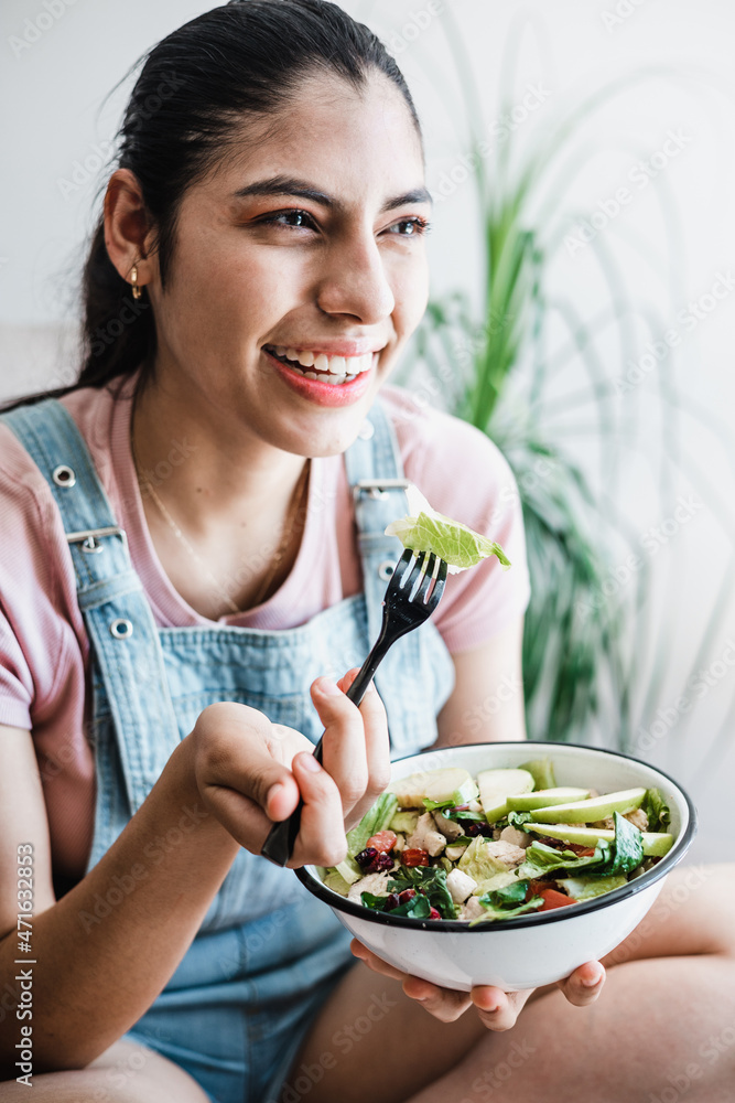 young latin woman eating vegetable or salad bowl, healthy food at home in Mexico Latin America young latin woman eating vegetable or salad bowl, healthy food at home in Mexico Latin America