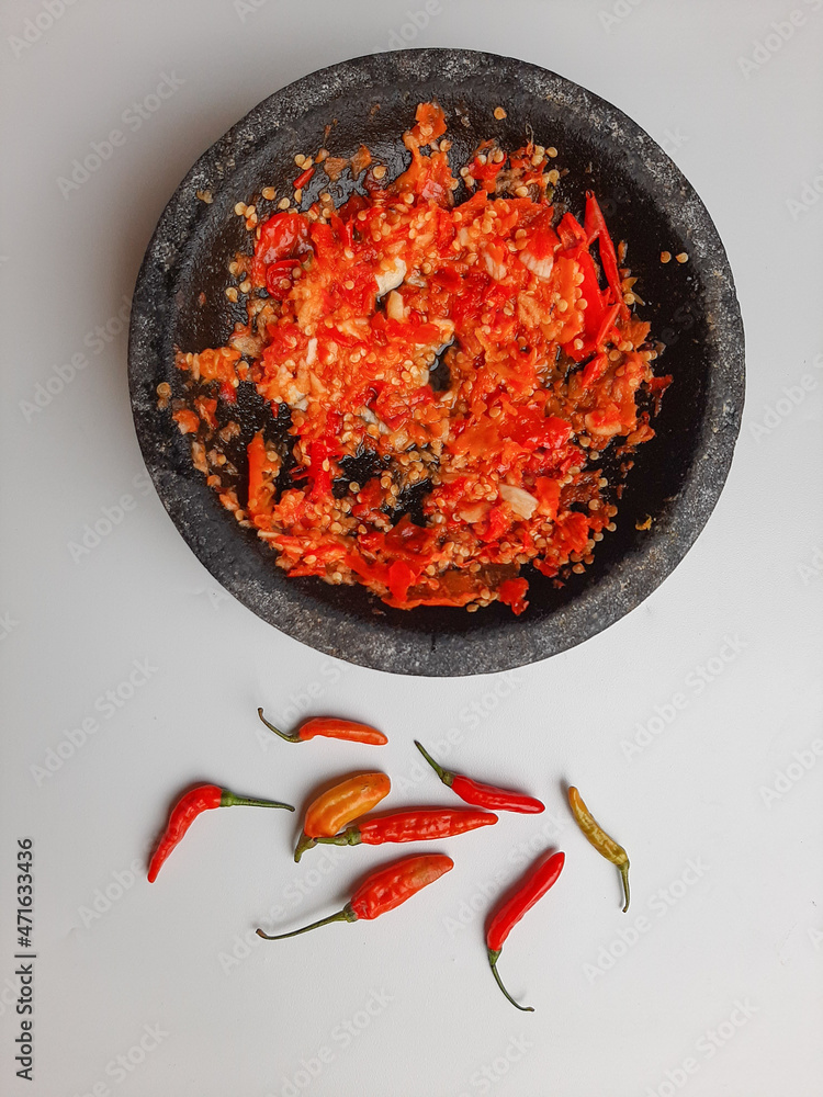 Sambal or traditional chili sauce from Indonesia, freshly made using stone mortar and pestle. Bird's eye chili spread around