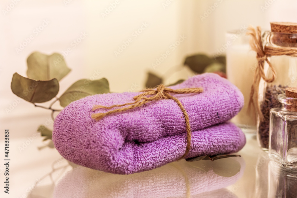 Folded lilac towel on spa relaxing bath background, jars with essential oil. Body treatment Folded lilac towel on spa relaxing bath background, jars with essential oil. Body treatment
