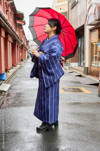 傘を持って東京の下町を歩く着物姿の日本人女性 © photok