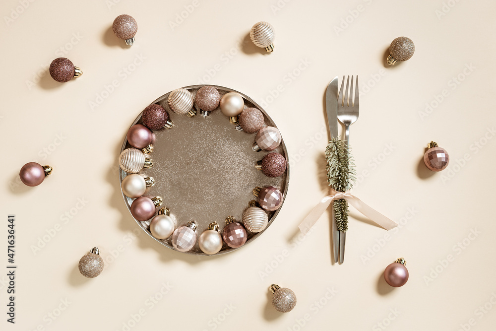 Christmas and New Year creative layout with plate, fork, knife decorated Christmas sparkling ball. Festive table decorations on pastel beige background. Winter holiday table setting Christmas and New Year creative layout with plate, fork, knife decorated Christmas sparkling ball. Festive table decorations on pastel beige background. Winter holiday table setting
