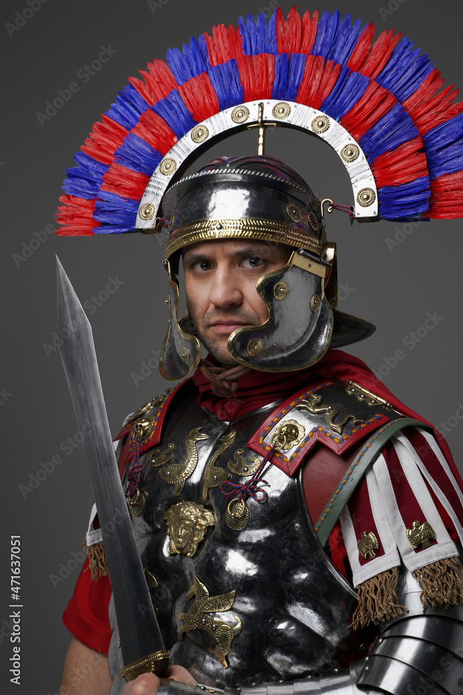 Proud roman soldier with gladius posing against gray background Proud roman soldier with gladius posing against gray background
