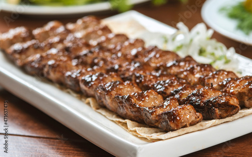 Fast food. Eastern food. Shish kebab, lyulya-kebab. Dishes of oriental cuisine lying in plte and decorated with greens and vegetables, sauces photo