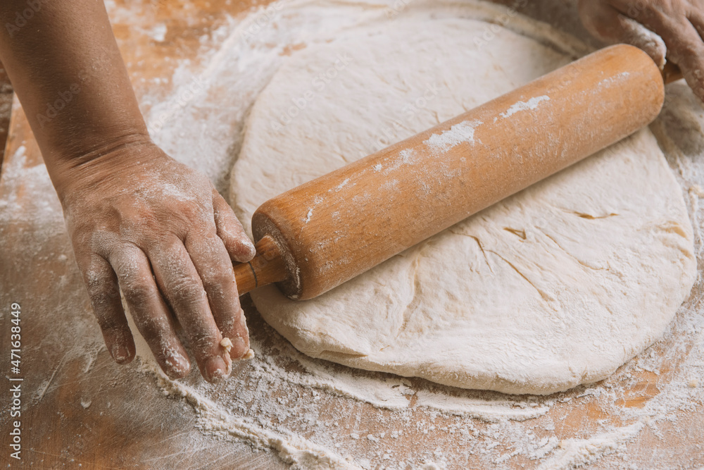 Chef is rolling the dough with the rolling pin on the on the table. Hands close-up.Cooking pasta, bread,spaghetti,khachapuri, food concept Chef is rolling the dough with the rolling pin on the on the table. Hands close-up.Cooking pasta, bread,spaghetti,khachapuri, food concept