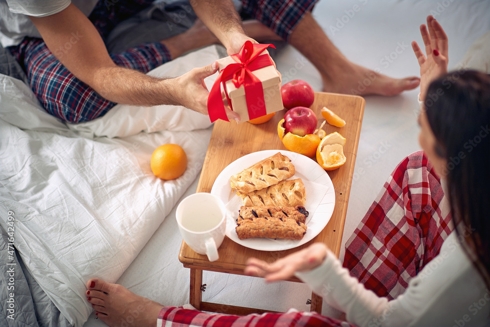 Christmas morning in the bed.Men on Christmas give a happy woman a gift. Christmas morning in the bed.Men on Christmas give a happy woman a gift.