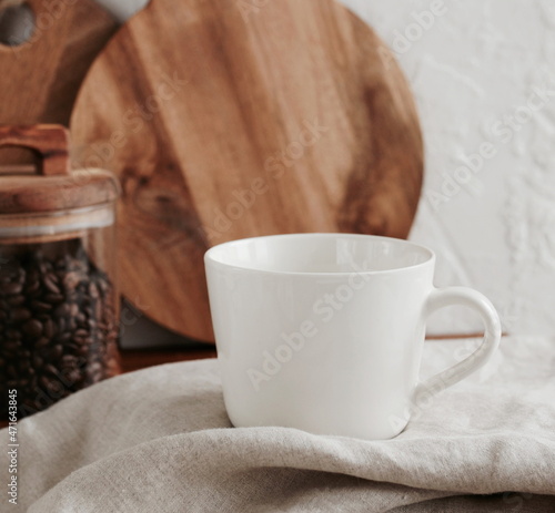 Coffee mug mockup on the beige linen tablecloth in the modern kitchen interior . copy space.Business food brand template.
