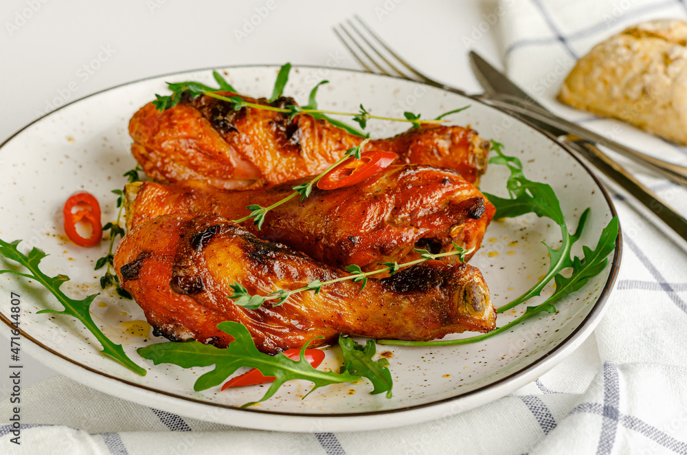 Roasted spicy chicken legs or drumsticks on a white dish. Delicious dinner or lunch concept.