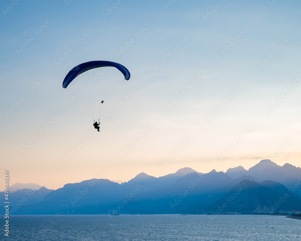 Silhouette of a man on a paraglider flying over the sea at sunset. Silhouette of a man on a paraglider flying over the sea at sunset.