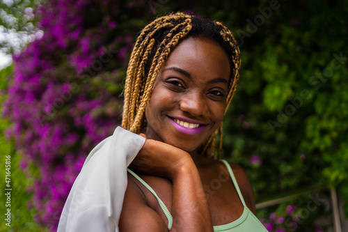 African woman smiling to the camera while posing on a garden