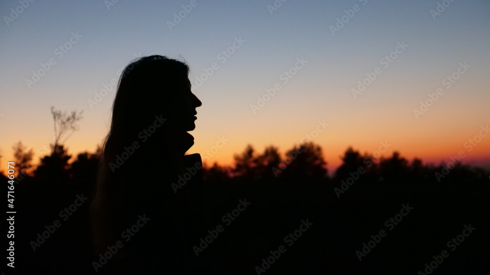 Silhouette of a person at sunset young woman, girl, teenager in profile close up
