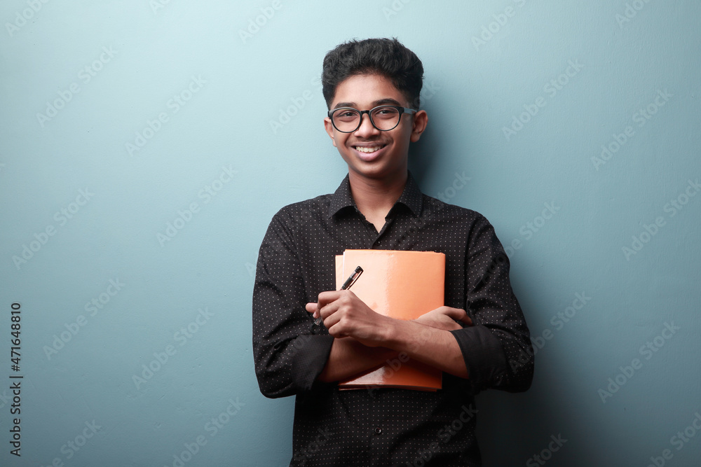 Smiling boy of Indian ethnicity holding note books in his hands Smiling boy of Indian ethnicity holding note books in his hands