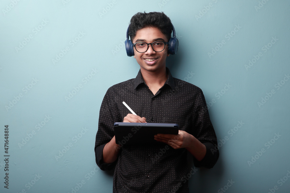 Portrait of a smiling young boy of Indian ethnicity holding a tablet phone in hand Portrait of a smiling young boy of Indian ethnicity holding a tablet phone in hand