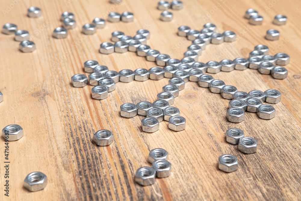 Homemade snowflake made of metal nuts on a wooden table. Winter symbol. Creative idea. New Year and Christmas holiday wait concept. Homemade snowflake made of metal nuts on a wooden table. Winter symbol. Creative idea. New Year and Christmas holiday wait concept.