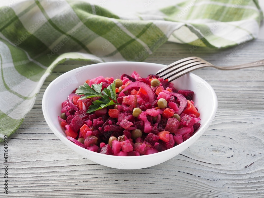 Seasonal salad vinaigrette with beetroot in a white bowl, napkin, fork on a white wooden table. Healthy food with vegetables for vegetarian dietary nutrition, closeup Seasonal salad vinaigrette with beetroot in a white bowl, napkin, fork on a white wooden table. Healthy food with vegetables for vegetarian dietary nutrition, closeup