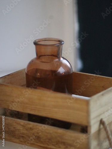 Glass brown jar in a wooden box on the windowsill