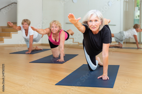Mature women exercising hands and knees balance during their group training.