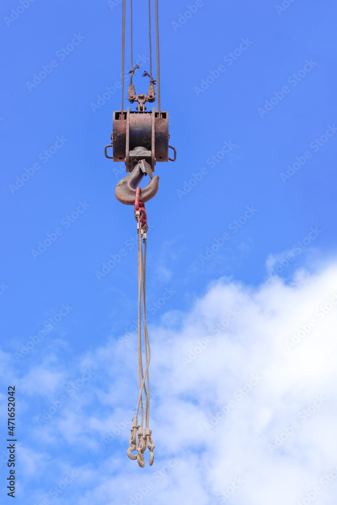 Metal crane hook against the background of the blue sky with the clouds Metal crane hook against the background of the blue sky with the clouds