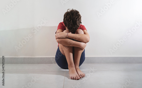 sad child sitting on the floor and crying on the knees. concept of abuse and home violence against children.