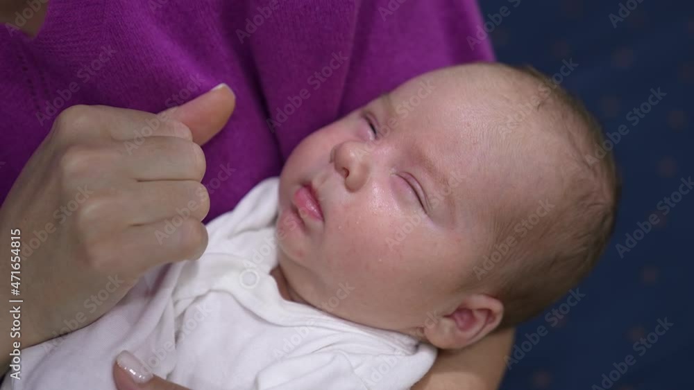 Slowly waking up baby opens and closes his eyes sleepily. Caring mother is pressing baby’s cheeks lovingly in attempt to wake him up. Close up. Slowly waking up baby opens and closes his eyes sleepily. Caring mother is pressing baby’s cheeks lovingly in attempt to wake him up. Close up.