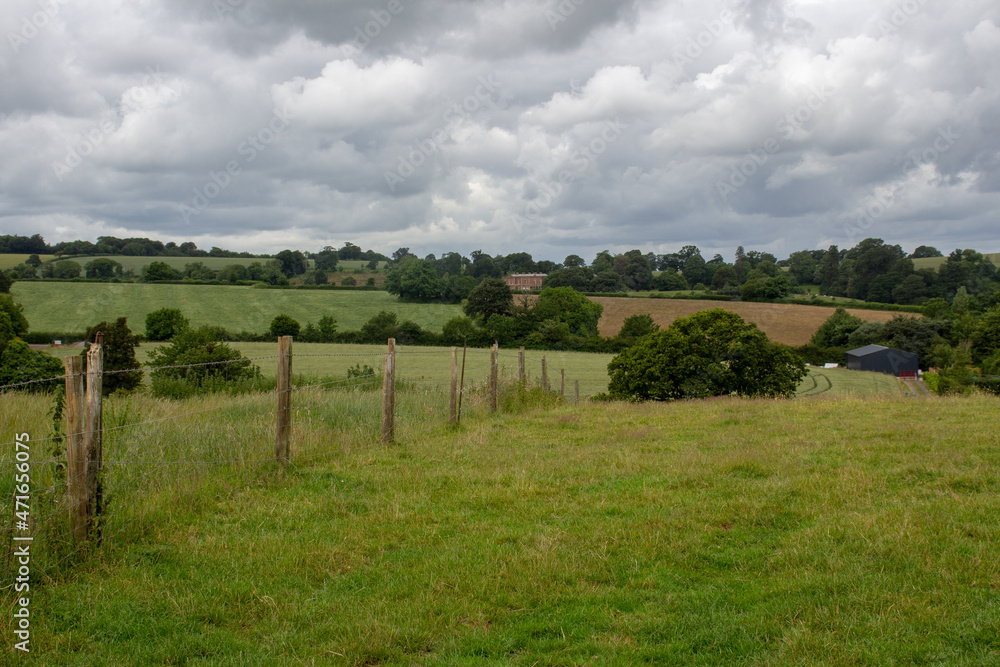 fencing and Devon hills and grazing land and a hedgerow in the background on a cloudy day