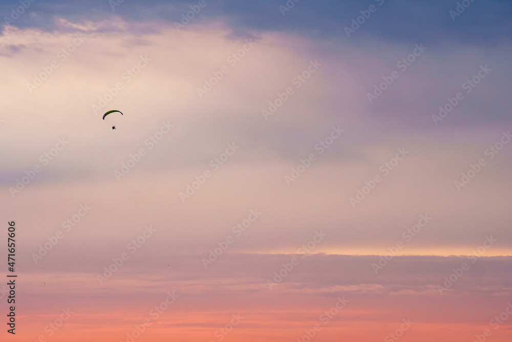 Silhouette of a paraplane (powered parachute) flying in magnificent pink evening sky. Balloon festival in Belgorod, Russia.