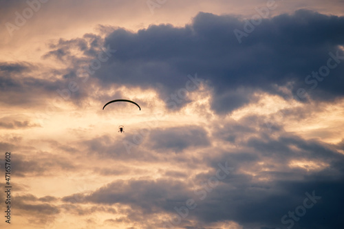 Silhouette of a paraplane (powered parachute) flying in magnificent golden sunset sky. Balloon festival in Belgorod, Russia.