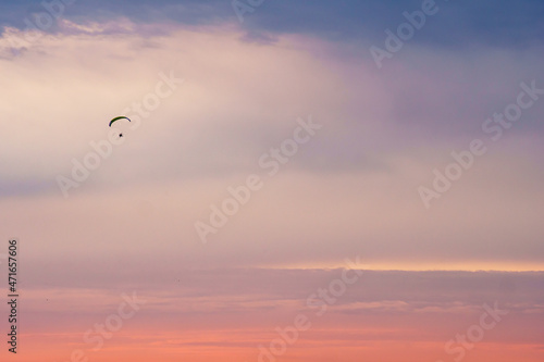Silhouette of a paraplane (powered parachute) flying in magnificent pink evening sky. Balloon festival in Belgorod, Russia.