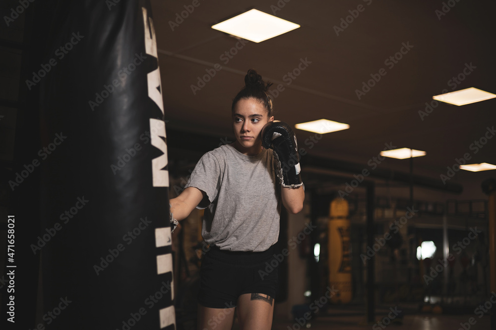 an underage girl hitting a punching bag.
an underage girl hitting a punching bag.