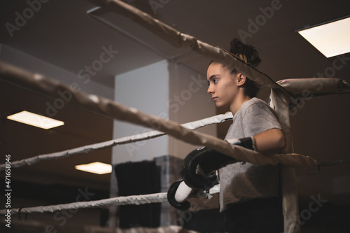 an underage girl leaning on a ring before boxing.