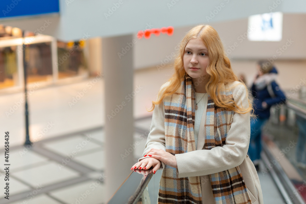 Young woman with long blond hair moving up on escalator Young woman with long blond hair moving up on escalator