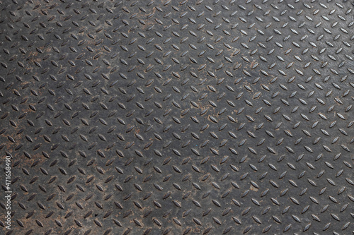 black diamond metal plate background, grunge texture of dark metallic sheet with small oval shape diagonal pattern, embossed surface prevents slipping for stair or walkway and ramp floor