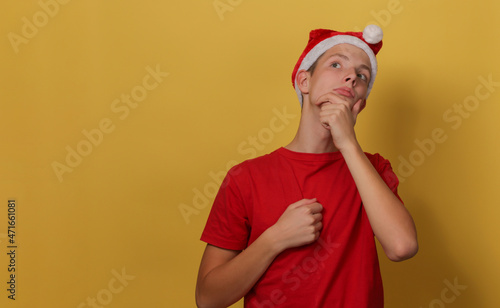 Portrait of an attractive boy 15 years old wearing a Santa hat in a pensive pose. © gelog67