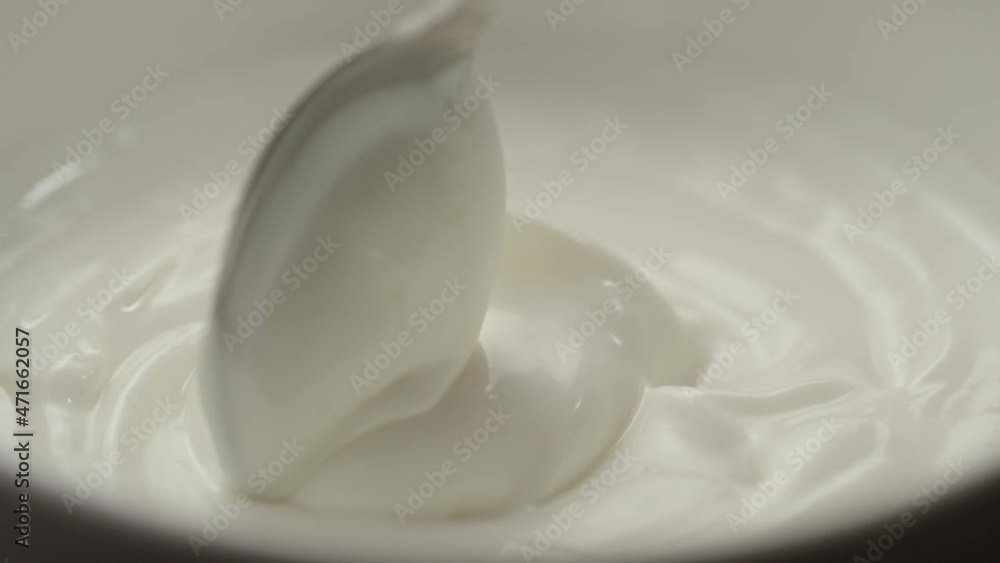 Slow motion macro shot of scooping white yogurt with a spoon Slow motion macro shot of scooping white yogurt with a spoon