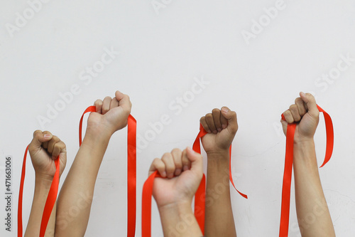 Close-up shot of people lift up their hands with red ribbon for AIDS awareness