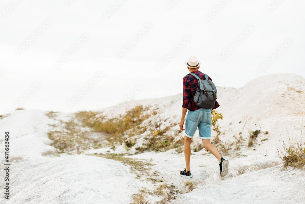 man with a backpack is strolling alone on a sandy beach in the mountains. Travel adventure lifestyle concept outdoors