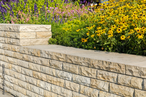 Decorative sandstone wall in the garden and yellow flowers.