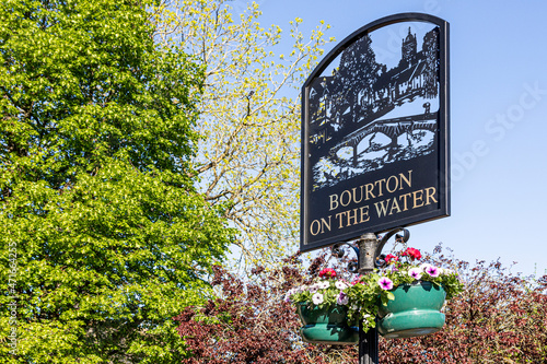 The village sign beside the River Windrush in the Cotswold village of Bourton on the Water, Gloucestershire UK photo