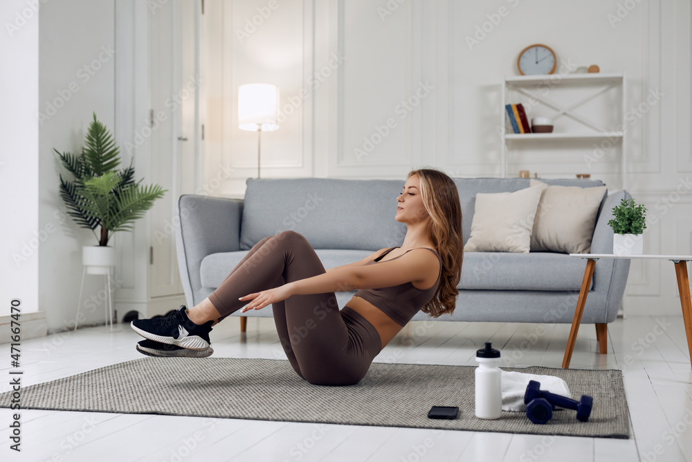 Young good looking woman in a brown suit doing exercises and working hard at home Young good looking woman in a brown suit doing exercises and working hard at home