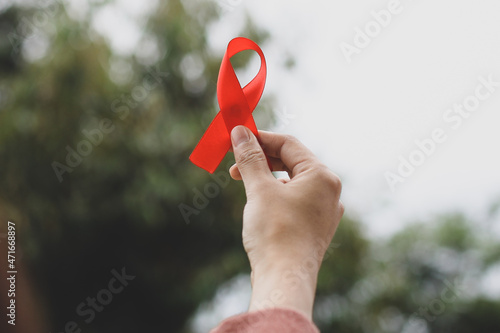 Closeup of a hand holding red awareness ribbon for World AIDS Day.