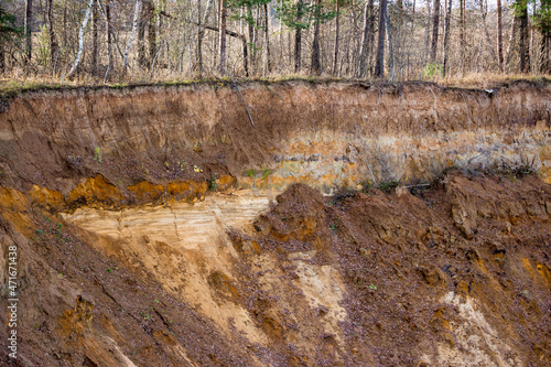 Fotografie Sharp steep cliff on a sandy quarry, layers of soil, sand and loam