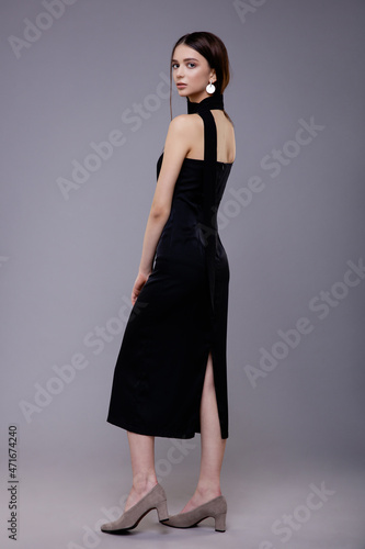 Fashion model in black dress, beautiful young woman. Studio shot. Gray background.  © SBekhinov