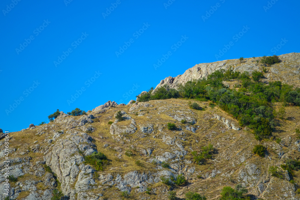 Path along the mountain to the top among bushes and stones against the blue sky in a hot southern country Path along the mountain to the top among bushes and stones against the blue sky in a hot southern country
