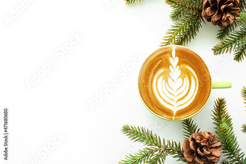 White table with cup of latte coffee and Christmas decoration with pine branches and pine cones. Christmas and new year celebration concept. Top view with copy space, flat lay.