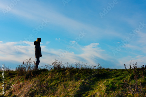 Person standing on a small hill looking out.