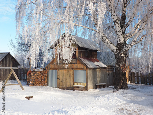 One winter frosty morning. Old house, street of a small Russian town. Russian wooden traditional house. Trees covered with hoarfrost. Winter. Russia, Ural, Perm region.