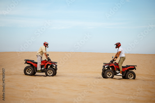 Two racers in helmets stand face to face on atvs