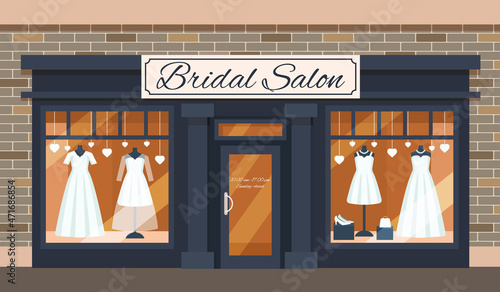 Vintage wedding shop store facade with large window, columns, brick wall.